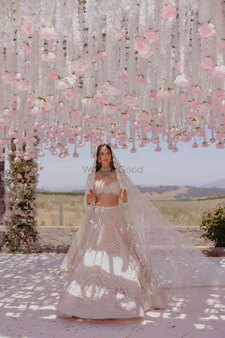Stunning bridal portrait with bride in a pastel lehenga and hanging floral decor elements in white and baby pink