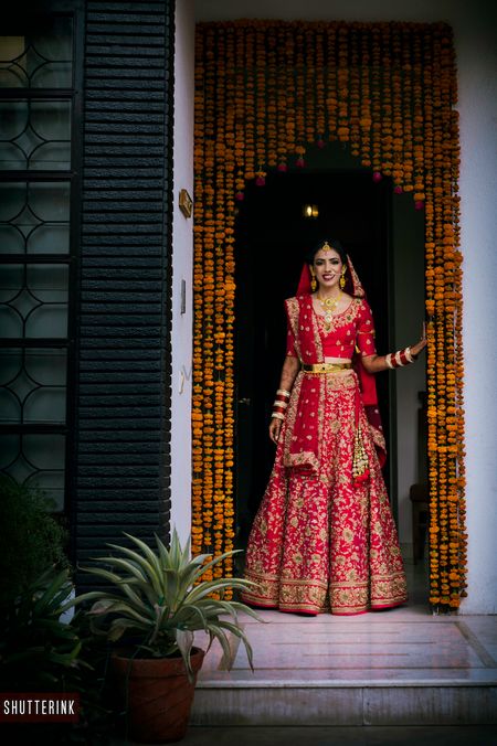 Photo of Red and gold bridal lehenga with waist belt