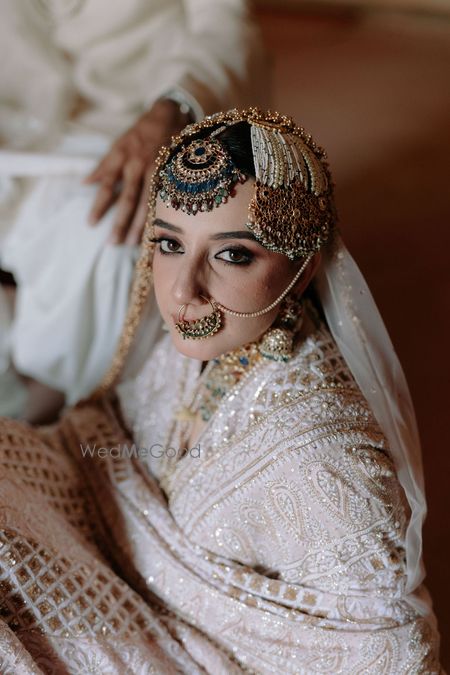 Oversized emerald maang tika with pearl passa and a delicate pearl nose ring for the bride