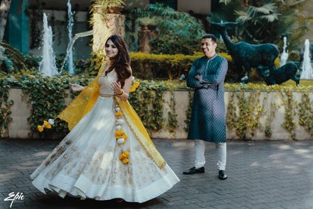Photo of A bride in a blue lehenga twirls as her groom looks on