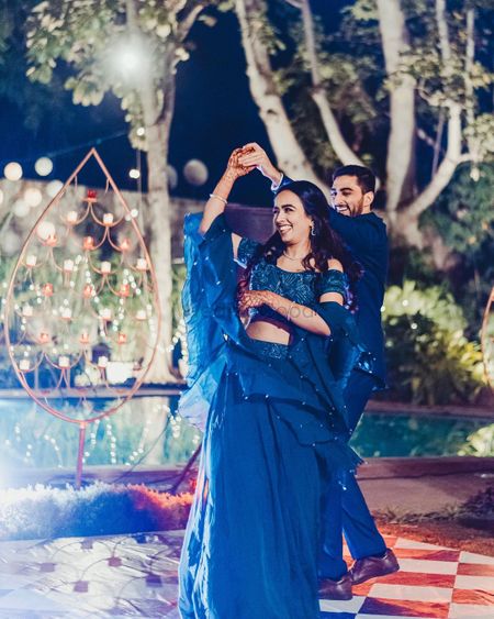 Photo of dancing couple shot with the bride in a blue cocktail lehenga