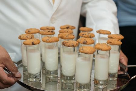 Photo of milk and cookies served in shot glasses for reception.