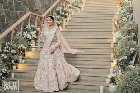 Bride walking down the stairs in a stunning white and pink lehenga on her wedding day