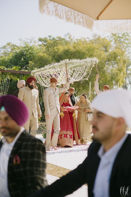 Photo of Candid shot of the bride entrying under a phoolon ki chaddar with her brothers