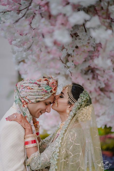A bride in green kissing her groom on the forehead