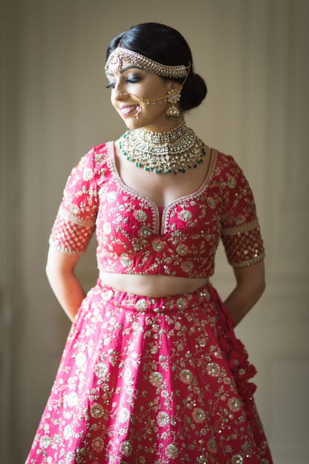 Photo of A bride in a red lehenga with a gold choker