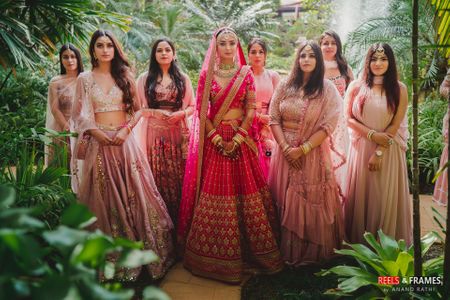 Bride in pink lehenga with coordinated bridesmaids in light pink outfits