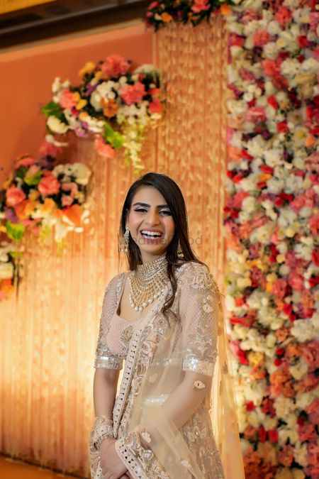 Bride in a pastel lehenga against a floral backdrop