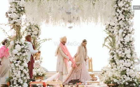 Photo of The couple talking pheras in a gorgeous all white and green mandap