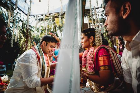 South indian nuptials with the couple divided by a sheet 