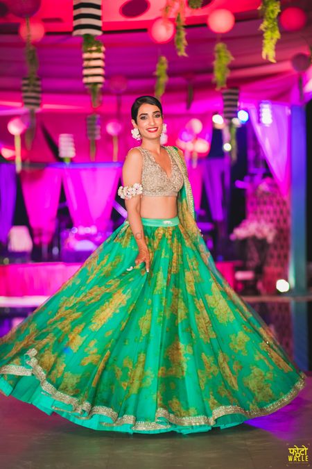 The bride twirling in a beautiful green floral lehenga and a silver blouse