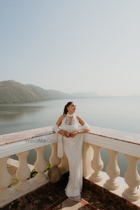 Photo of Gorgeous bridal portrait with the bride in a white saree with a halter neck blouse and white jewellery and a sleek hairstyle to match