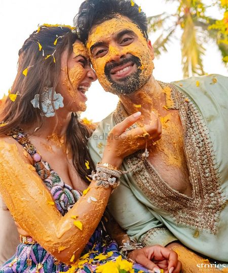 Fun haldi photo of the couple smeared in haldi with bride in some unique accessories
