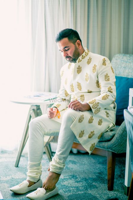 Photo of Groom in gold and white sherwani with buti design