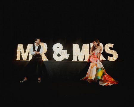 Fun Mr and Mrs signage from the reception decor with the couple posing in front 