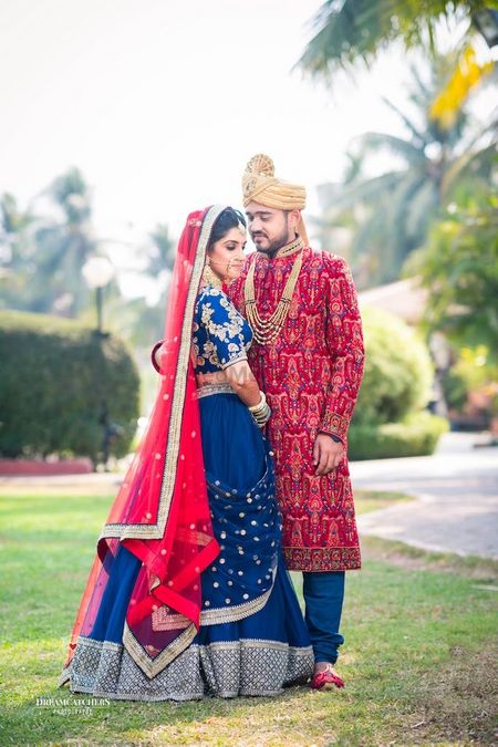 Photo of Offbeat bridal lehenga and groom in red