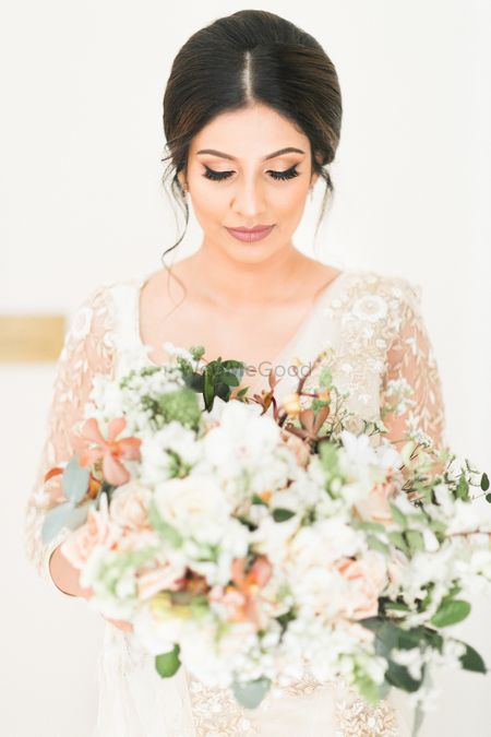 Bride with elegant hairdo holding bouquet 