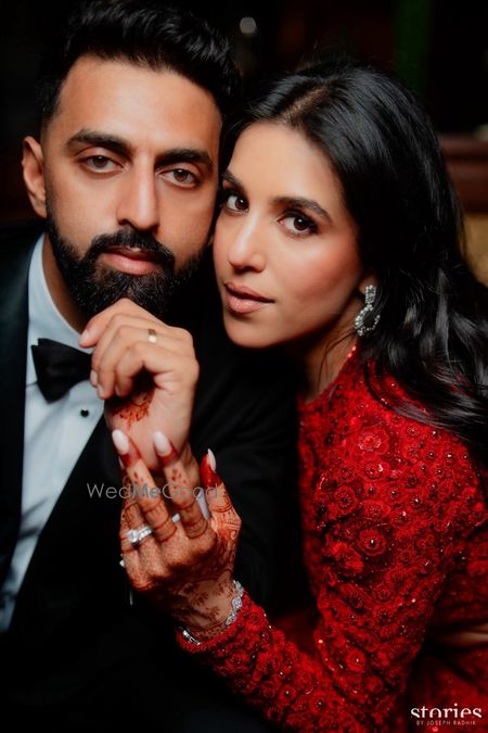Classic couple portrait with the bride in a red lehenga and groom in black tuxedo