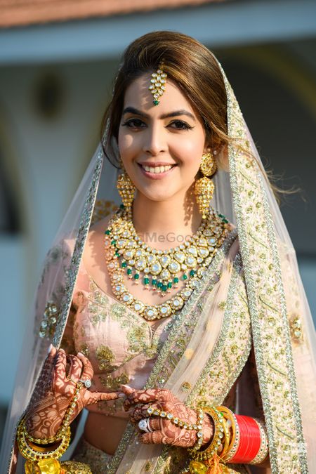 A close-up shot of a bride in a blush pink and gold lehenga for her wedding