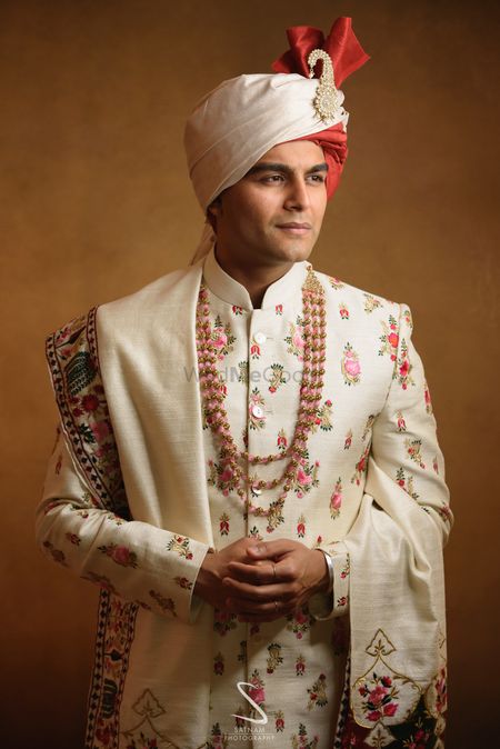 groom in a white floral sherwani and safa