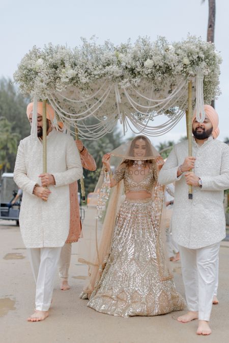 Bride in gold designer lehenga entering with phoolon ki chadar 