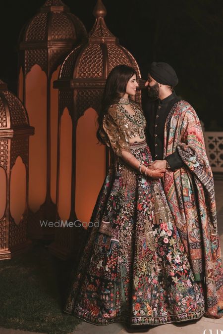 Photo of Couple co-ordinated in black outfits with bride in heavy jewellery and open hair