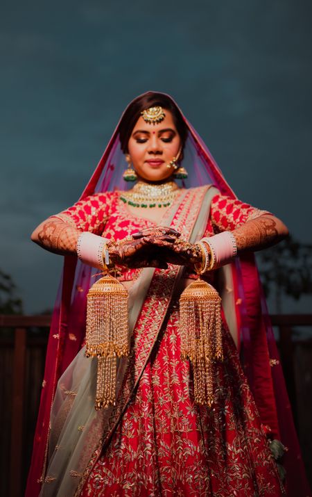 bride wearing a red lehenga and pastel chooda 