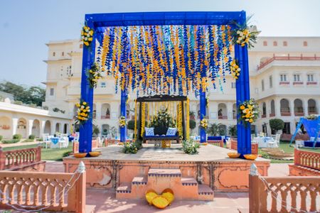 Photo of haldi stage backdrop idea with blue and yellow elements
