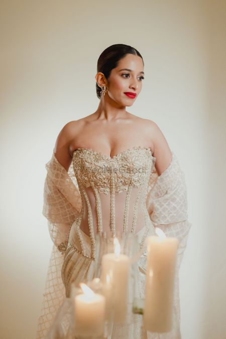 Glam bridal look in a sheer and strapless gown in beige and gold with a dupatta