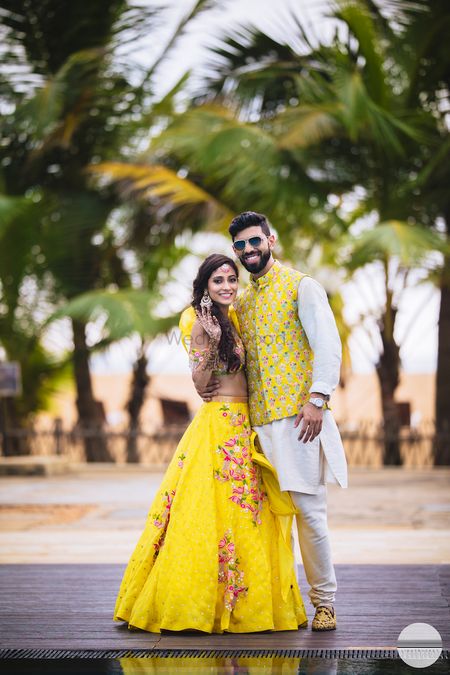 A bride in groom in coordinated yellow mehendi outfits 
