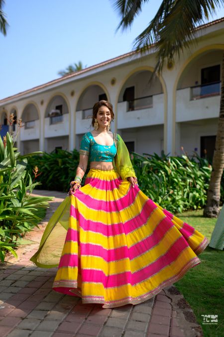 A bride in a multi-colored lehenga for her morning mehndi ceremony