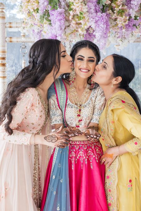 Bride posing with her mother and sister on her Mehndi ceremony.