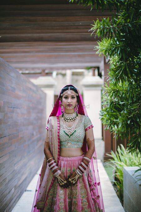 Bride posing in green and pink bridal lehenga with double dupatta