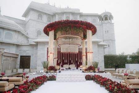 A circular open air mandap with white and red flowers