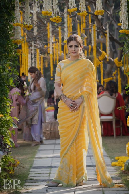 Photo of sister of the bride in yellow striped saree on mehendi