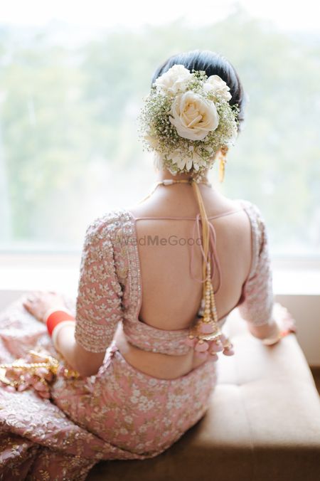 Bride wearing a floral bouquet bun with a pink lehenga.