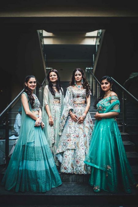 A bride in powder blue lehenga poses with her bridesmaids