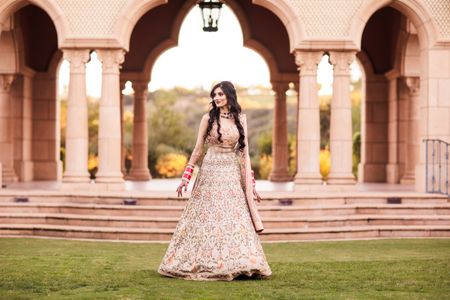 Bride in a subtle light pink lehenga for her engagement outdoors