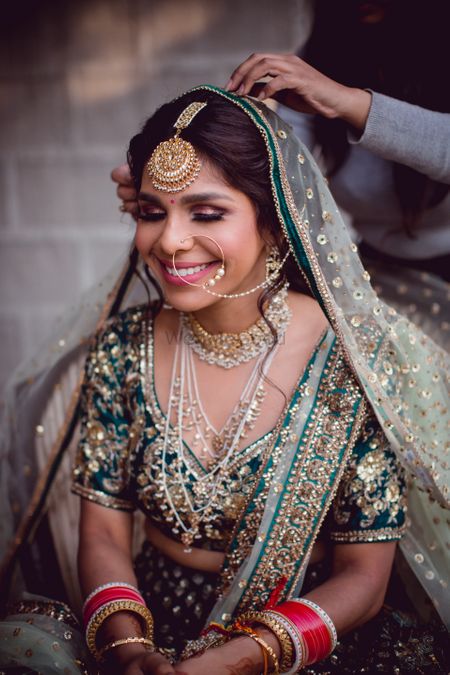 Photo of A bride in a dark green lehenga with a satlada for her wedding