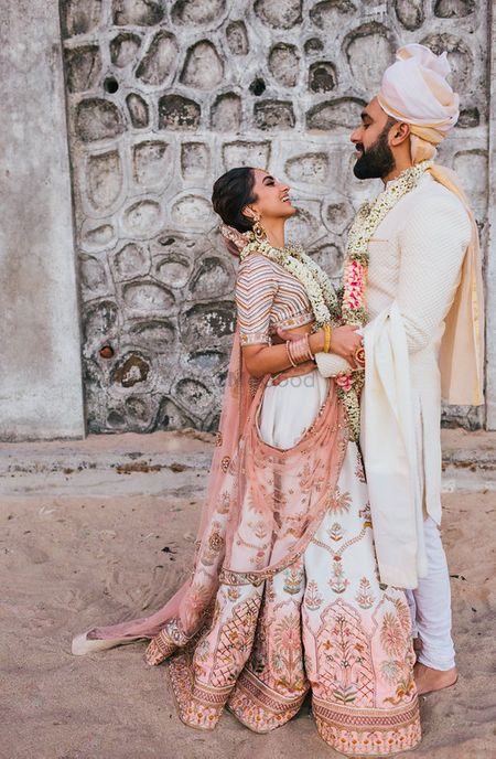 Photo of Bride and groom in ivory with customised lehenga