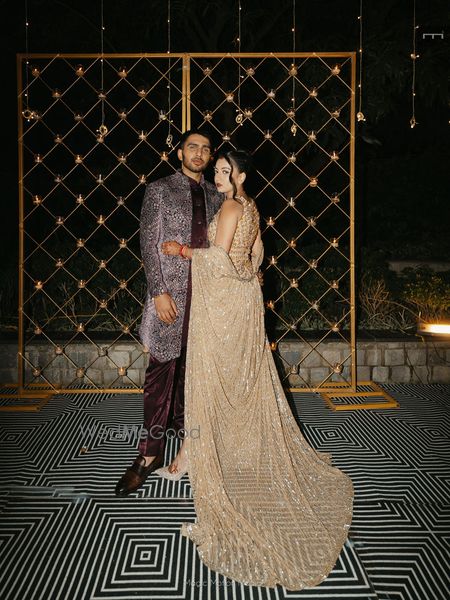 Bride and groom on the cocktail night in co-ordinated sprakly outfits with the bride in a gold indo-western outfit