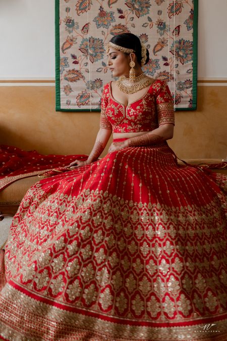 bride in a red and gold lehenga getting ready shot