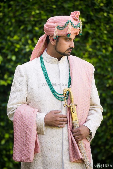 Groom in white sherwani with pink turban and green beads