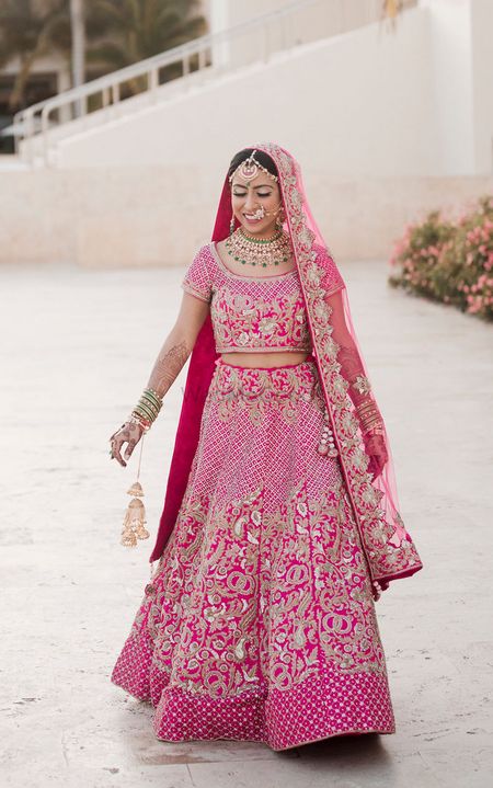 Bride in bright pink lehenga with embroidery all over it