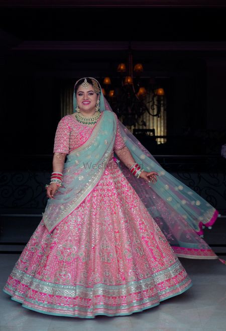 Twirling bride in pretty pink and turquoise lehenga 