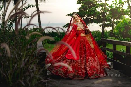 Classic happy bride posing in her red wedding lehenga for a beach wedding