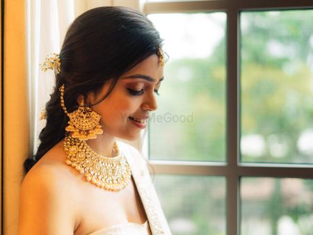 A bride flaunting her gold choker and waterfall earrings with multiple jhumkis
