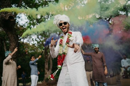 Fun groom shot with groom dancing and smoke bombs in the background