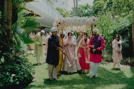 A bridal entry with the bride in a pink lehega, and under the phoolon ki chaadar! 