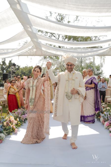 Just married shot of the couple with white jaimalas and pastel outfits